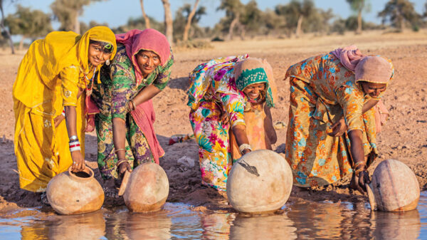 Women fill jars with water from the river.