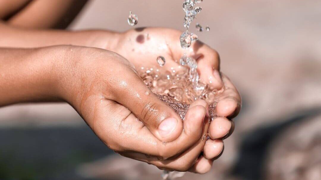 Hands collecting water from tap.
Economic water scarcity.